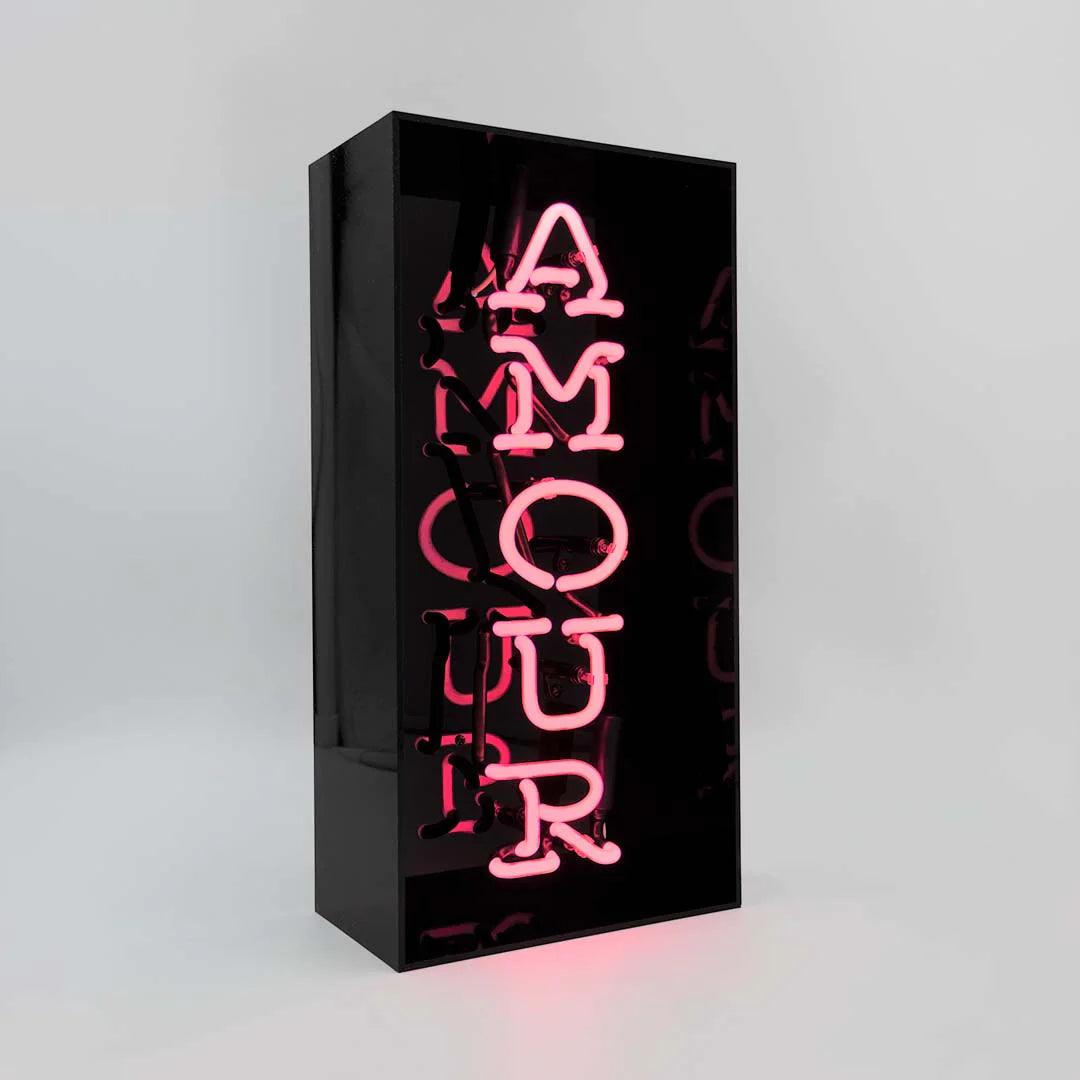 TOM NEON Glas Neon Box 'Amour'. Stilvolle Neonbeleuchtung mit dem Wort 'Amour' in einer eleganten Glasbox. Perfekt für eine romantische und moderne Raumdekoration.