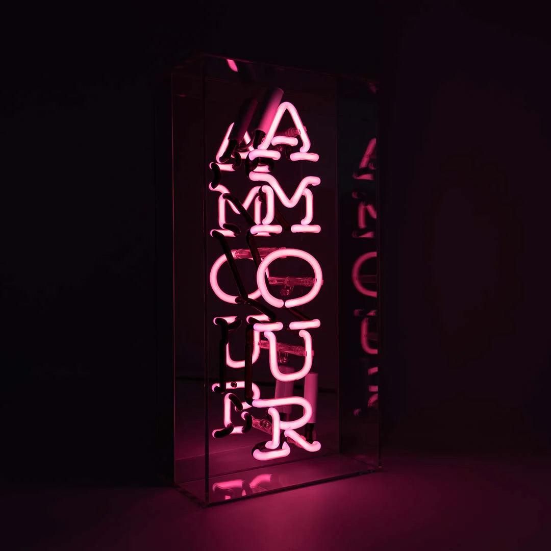 TOM NEON Glas Neon Box 'Amour'. Stilvolle Neonbeleuchtung mit dem Wort 'Amour' in einer eleganten Glasbox. Perfekt für eine romantische und moderne Raumdekoration.