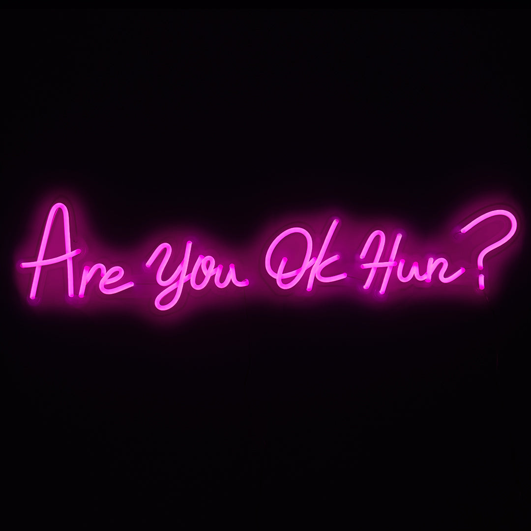 TOM NEON LED Schriftzug 'Are you ok Hun?'. Leuchtender Neonschriftzug mit der Frage 'Are you ok Hun?' in stilvollen Buchstaben. Ideal für moderne und ausdrucksstarke Raumgestaltung.